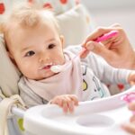 Bebeluș hrănit cu iaurt folosind o linguriță, în timpul diversificării alimentației.
