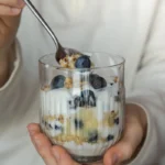 Pahar cu iaurt si afine, doua alimente bogate in nutrienti.