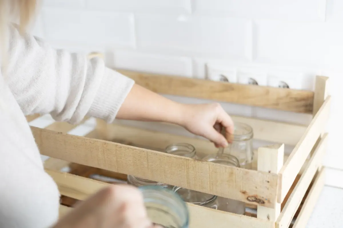Femeie pregătind ambalaje din sticle de produse lactate pentru reciclare 