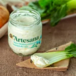 Un borcan de branza cremoasa usoara de vaci de la Artesana desfacut si o felie de pack choi cu branza langa el