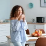 Tanara rasfatandu-se cu un pahar de kefir delicios acasa, in bucatarie. 