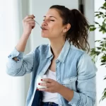 Femeie care consumă iaurt dintr-un borcan