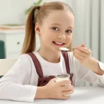 Fetiță care mănâncă iaurt din borcan 