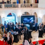 Evenimentul Romanian Hospitality Awards 2025, unde Artesana este partener, participanți în foyerul somptuos discutând lângă standul brandului și panoul de premiere.