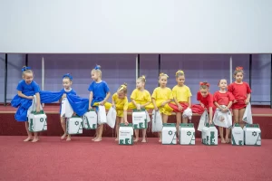 Copii sportivi îmbrăcați în costume colorate, aliniați pe scenă cu pachete Artesana, în cadrul Galei Campionilor – 50 de ani Clubul Sportiv Școlar Bârlad, 20 decembrie 2025.”
