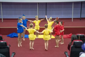Moment artistic susținut de copii sportivi, îmbrăcați în costume galben, albastru și roșu, pe scena Galei Campionilor – 50 de ani Clubul Sportiv Școlar Bârlad.