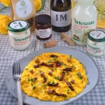Risotto alla milanese cu infuzie de șofran, servit pe farfurie gri, preparat cu smântână și iaurt Artesana, alături de ingrediente naturale și vin alb pe masă cu față în carouri.