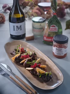 Ficăței de pui gătiți cu smântână aromatizată Artesana, serviți elegant pe platou ceramic, alături de vin roșu și ingrediente gourmet