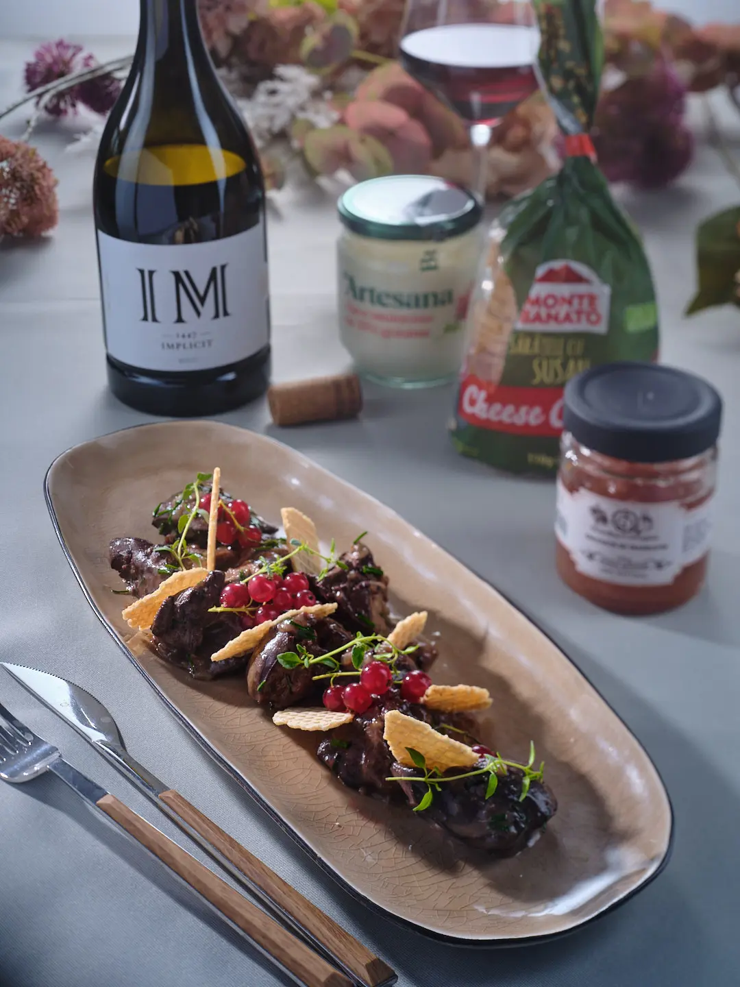 Ficăței de pui gătiți cu smântână aromatizată Artesana, serviți elegant pe platou ceramic, alături de vin roșu și ingrediente gourmet
