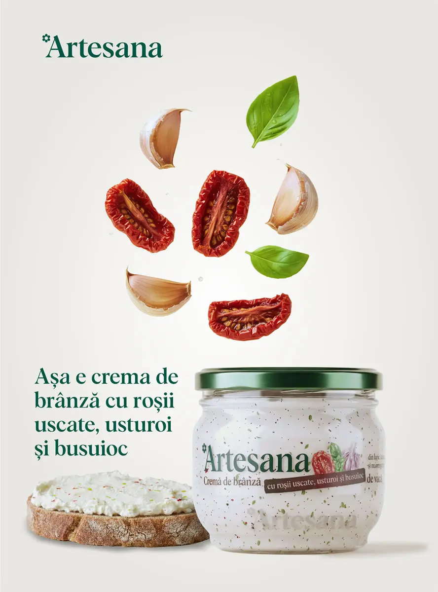 Crema de brânză Artesana cu roșii uscate, usturoi și busuioc, în borcan de sticlă cu capac verde, alături de o felie de pâine unsă și ingrediente proaspete – roșii uscate, căței de usturoi și frunze de busuioc – pe fundal deschis.