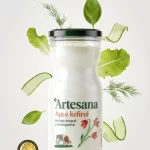 Kefir Artesana din lapte integral și neomogenizat, 350 ml, ambalat în borcan de sticlă cu capac negru, decorat cu ilustrație florală și vacă, înconjurat de frunze verzi, felii de castravete și mărar, sigiliu de calitate Qudal – Artesana, Artizanii laptelui.