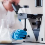 Om de știință care analizează laptele la microscop