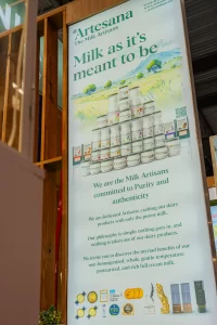 Panou Artesana la stand expozițional cu mesajul „Milk as it’s meant to be”, prezentând gama de produse lactate artizanale și valorile brandului Artesana.