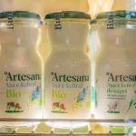 Sticle cu kefir Bio și kefir din lapte de capră Artesana expuse într-o vitrină frigorifică la un târg de profil.