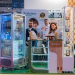 Stand Artesana la târg alimentar, cu echipa Milk Artisans prezentând iaurturi și lactate artizanale în vitrină frigorifică, degustare de produse și branding vizibil Artesana.