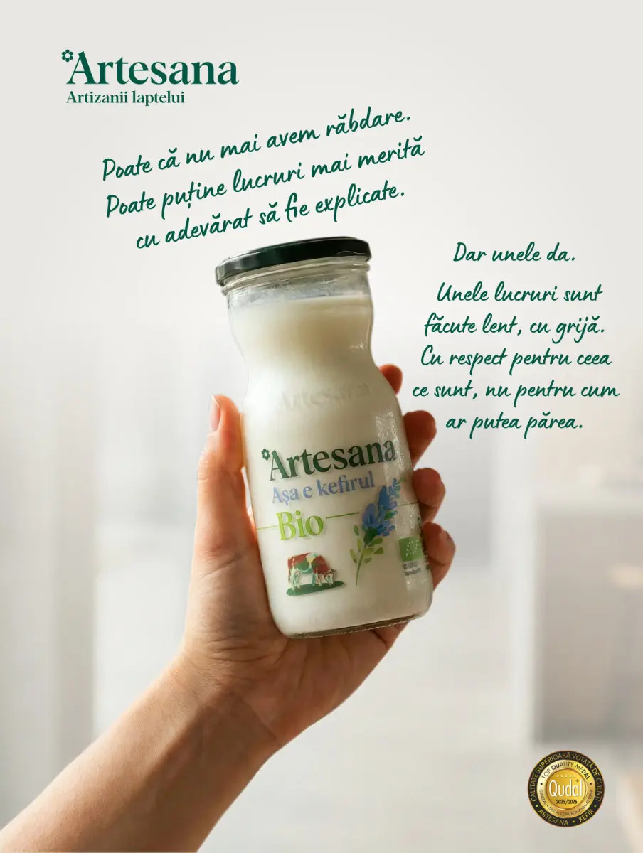 Mână ținând o sticlă de kefir Bio Artesana din lapte de vacă, produs artizanal, pasteurizat la temperatură blândă, ambalat în sticlă, brand Artesana - artizanii laptelui, mesaj despre produse făcute lent și cu grijă