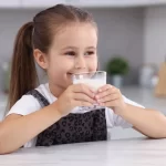 Fetita care bea un pahar de sana