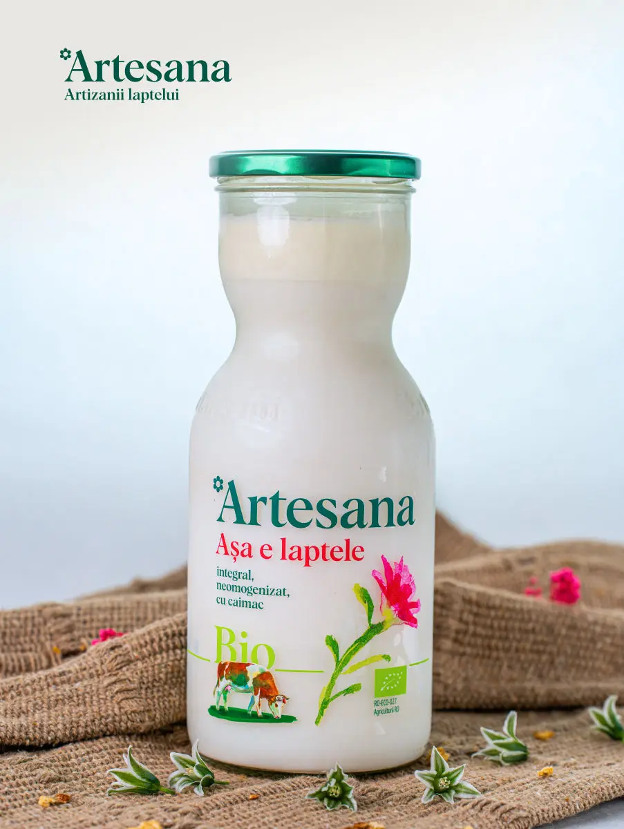 Sticlă de lapte bio Artesana integral, neomogenizat, cu caimac, ambalat în borcan de sticlă, pe fundal rustic din pânză, produs natural artizanal din România