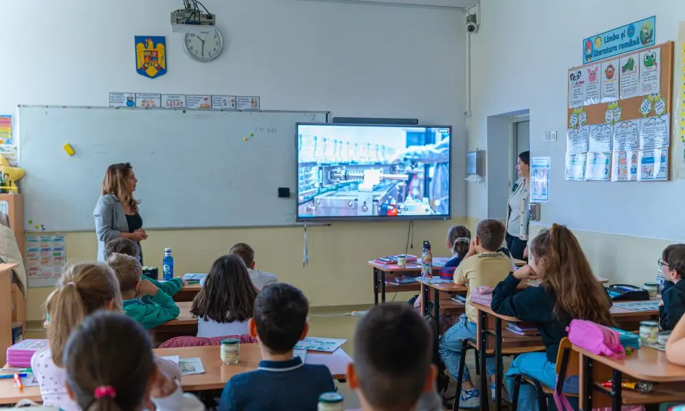 Elevi urmăresc o prezentare despre procesarea laptelui și fabrica Artesana, în cadrul unei activități educaționale desfășurate la școală.