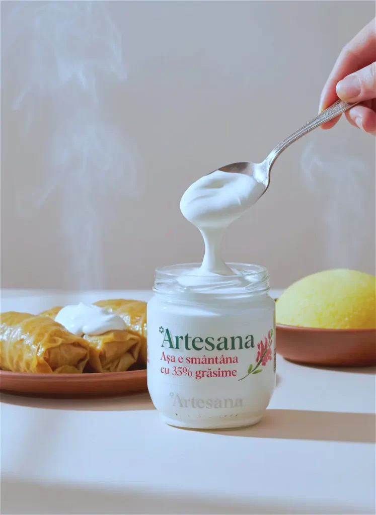 Smântână artizanală Artesana 35% grăsime într-un borcan de sticlă, luată cu lingura, alături de plăcinte calde și mămăligă, concept de produs natural și cremos