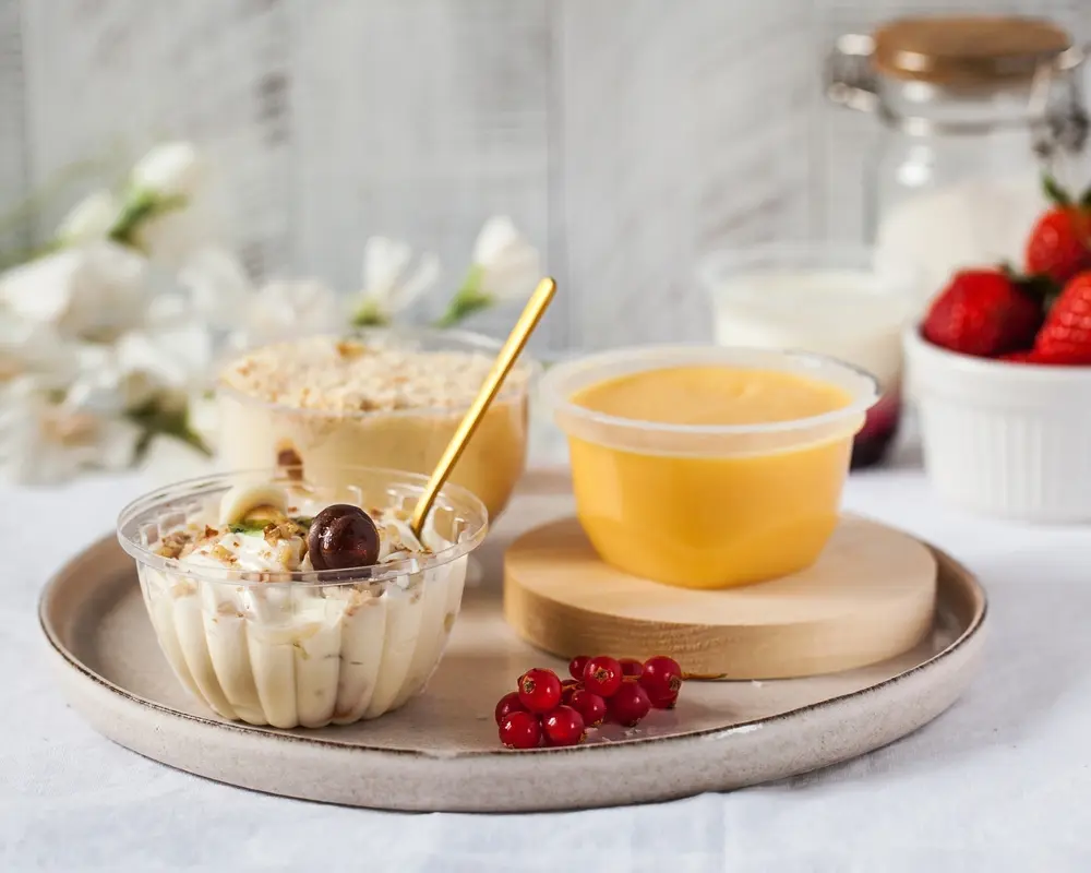 Deserturi pe bază de lactate – iaurt cremos cu topping de nuci și fructe, budincă și piure de fructe, servite elegant pe tavă, concept de gustare sănătoasă și naturală