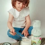 Copil mic savurând iaurt din lapte bio Artesana, alimentație naturală pentru copii, produs lactat artizanal sănătos