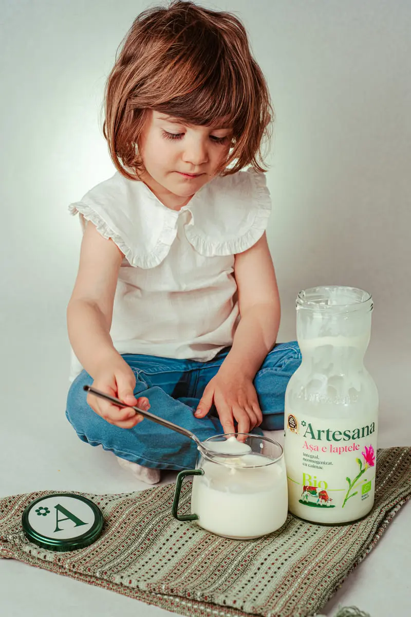 Copil mic savurând iaurt din lapte bio Artesana, alimentație naturală pentru copii, produs lactat artizanal sănătos