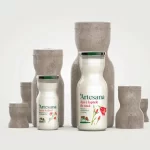Sticle Artesana de lapte și kefir, integrate într-o compoziție artistică inspirată de Masa Tăcerii a lui Constantin Brâncuși, cu forme sculpturale din piatră.
