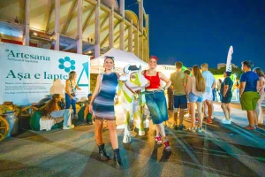 Participanți la roata norocului Artesana, lângă standul în formă de sticlă de lapte de la SAGA Festival 2026.