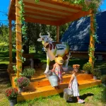 Două fetițe cu găleți, lângă vaca Artesana, în decorul rural amenajat la Family Farm Fest.