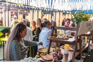 Vizitatoare alege brânzeturi de pe rafturile din lemn ale cheese barului Artesana, la RO-Wine 2026.