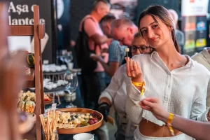 Vizitatoare ține o bucățică de brânză pentru degustare la standul Artesana de la RO-Wine 2026.