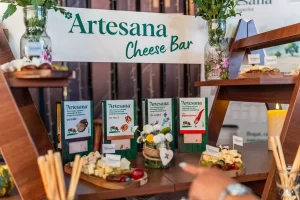Cheese bar Artesana la RO-Wine 2026, cu brânzeturi maturate în ambalaje și cubulețe pregătite pentru degustare.