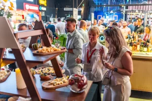 Vizitatori cu pahare de vin discută cu echipa Artesana la cheese barul de la RO-Wine 2026.