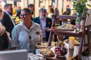 Reprezentanta Artesana întâmpină vizitatorii lângă platourile cu brânzeturi, la RO-Wine 2026.
