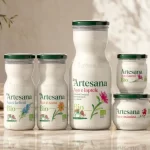 Produse lactate Bio Certificate Ecologic Artesana - kefir, sana, lapte si smantana Bio in borcanele si sticlele lor pe un fundal crem, insorit si linistitor