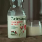 Sticla de lapte Artesana la un litru langa un pahar de lapte pe o masa intr-un decor tomnatic